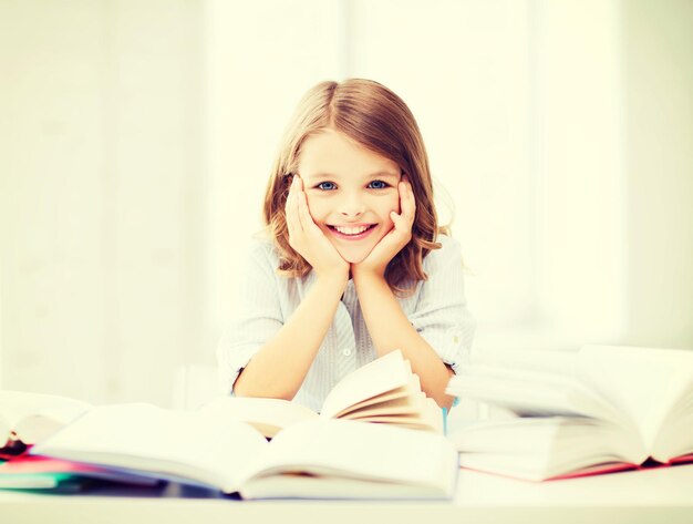 educación y concepto escolar - niña estudiante que estudia y lee libros en la escuela