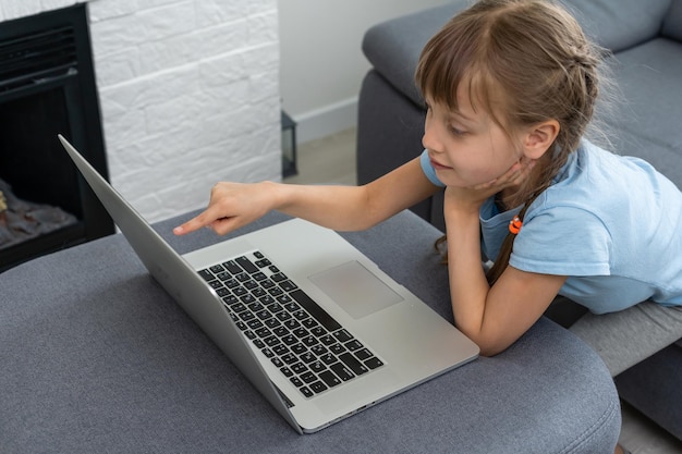 La educación a distancia. Niña alegre con auriculares usando laptop estudiando a través del sistema de aprendizaje electrónico en línea.