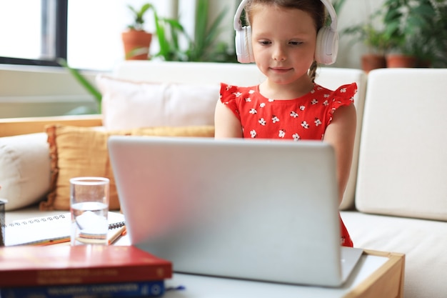 La educación a distancia. Niña alegre con ordenador portátil estudiando a través del sistema de e-learning en línea.