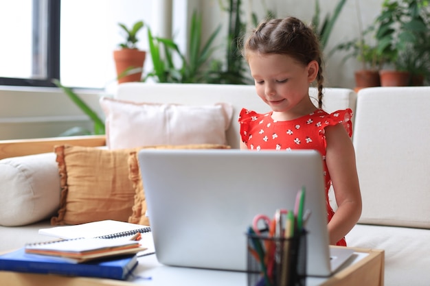 La educación a distancia. Niña alegre con ordenador portátil estudiando a través del sistema de e-learning en línea.