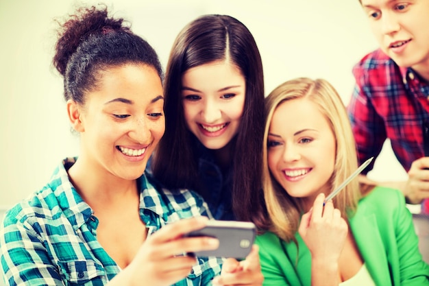 educación e internet - estudiantes sonrientes mirando el teléfono inteligente