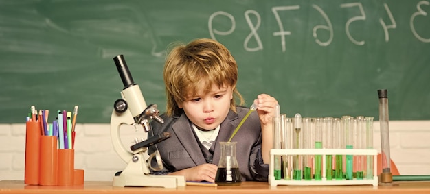 Educación escolar Explorar moléculas biológicas Niño genio bebé Concepto de tecnología y ciencia Niño cerca de microscopio y tubos de ensayo en el aula de la escuela Niño estudia biología y química en la escuela