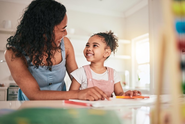 Educación escuela en casa y madre e hijo felices en una cocina para escribir tareas y estudiar juntos Aprendizaje remoto y niña con mamá sonríe y emocionada por la actividad educativa divertida