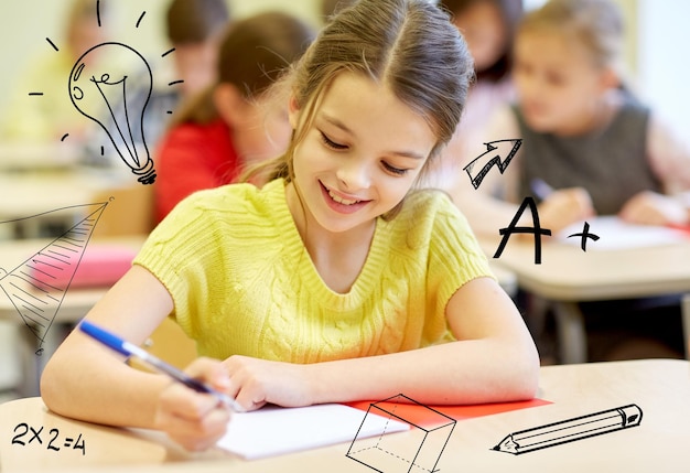 educación, escuela primaria, aprendizaje y concepto de personas - grupo de escolares con cuadernos escribiendo pruebas en el aula sobre garabatos