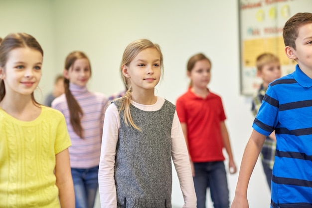 educación, escuela primaria, bebidas, niños y concepto de personas - grupo de escolares sonrientes caminando en el pasillo