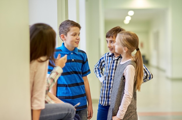 educación, escuela primaria, niños, descanso y concepto de personas - grupo de escolares sonrientes hablando en el pasillo