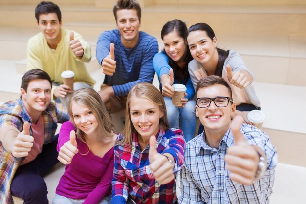 educación, escuela secundaria, amistad, bebidas y concepto de personas - grupo de estudiantes sonrientes con tazas de café de papel mostrando gestos de aprobación