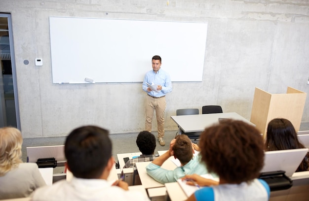 educación, escuela secundaria, universidad, enseñanza y concepto de personas - grupo de estudiantes internacionales y profesores con papeles en una pizarra blanca en una conferencia