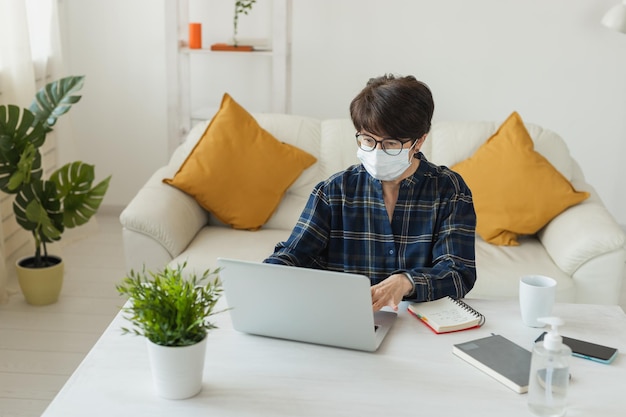 Foto educación de formación en línea y trabajo independiente. la computadora, la computadora portátil y la mujer de mediana edad trabajan de forma remota. pandemia de coronavirus en el mundo. aislamiento