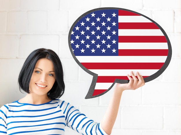 Foto educación, idioma extranjero, inglés, gente y concepto de comunicación - mujer sonriente sosteniendo una burbuja de texto de bandera estadounidense