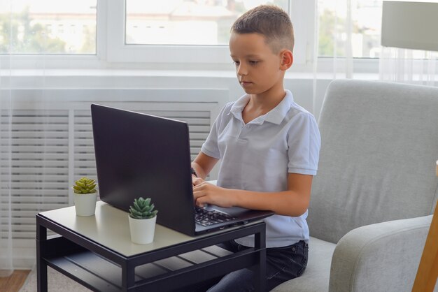 Educación en línea de aprendizaje a distancia Un niño escolar estudia en casa y hace la tarea escolar