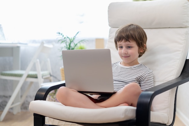 Educación en línea de aprendizaje a distancia sonrisa caucásica chico chico estudiando en casa con portátil y