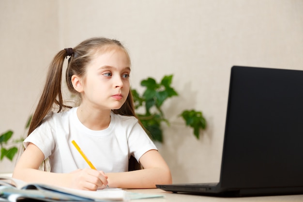 Educación en línea a distancia. Colegiala estudiando en casa