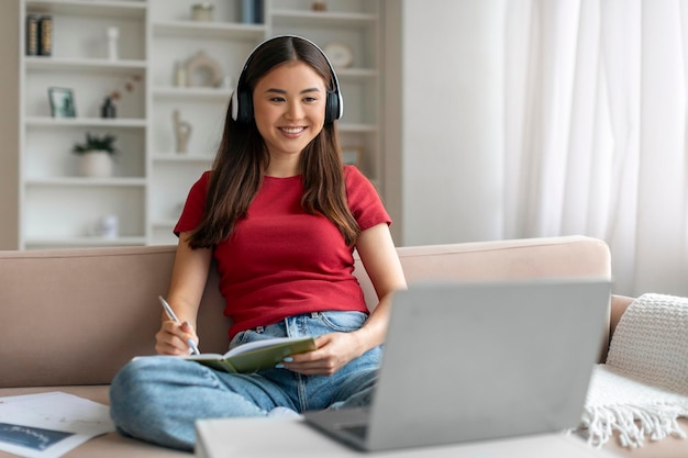 Educación en línea joven asiática con auriculares estudia con portátil en casa