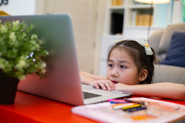 Educación en línea Niño asiático que usa la computadora portátil para aprender y estudiar en la sala de estar Concepto de escuela en casa.