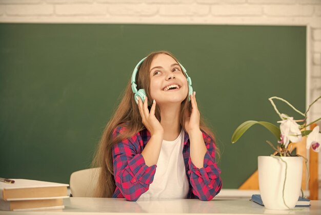 Educación en línea regreso a la escuela alegre jovencita en auriculares amante de la música