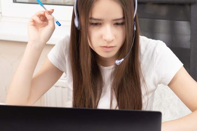 Educación en línea. Webinar. Un estudiante en casa se dedica a la formación, escucha atentamente y mira una conferencia en una computadora portátil con un micrófono en auriculares