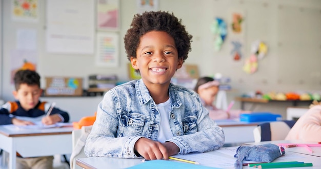 La educación de la sonrisa y la escritura con el niño en el aula para aprender conocimiento y estudio Beca feliz y futuro con el retrato de un joven estudiante en la escuela para el examen de la academia prueba y proyecto