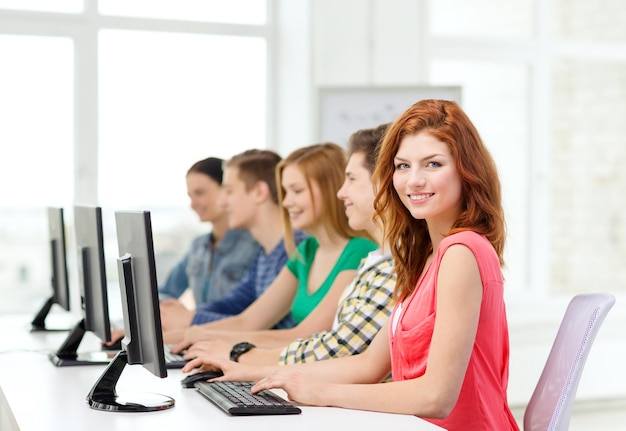 educación, tecnología y concepto escolar - estudiante sonriente con compañeros de clase en clase de computación en la escuela