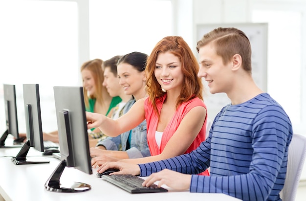 educación, tecnología y concepto escolar - estudiante sonriente con compañeros de clase en clase de computación en la escuela