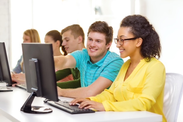 educación, tecnología y concepto escolar - estudiantes sonrientes en clase de computación en la escuela