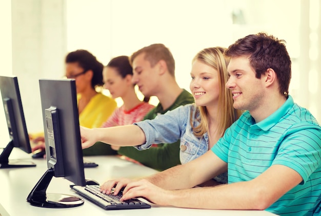 educación, tecnología y concepto escolar - estudiantes sonrientes en clase de computación en la escuela