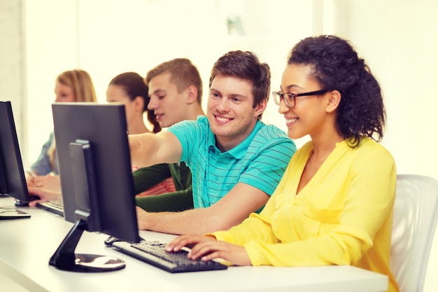 educación, tecnología y concepto escolar - estudiantes sonrientes en clase de computación en la escuela