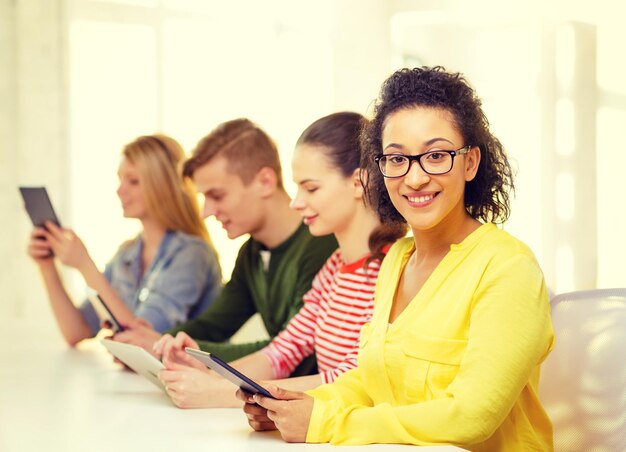 educación, tecnología y concepto de internet - estudiantes sonrientes con tablet pc y amigas en la parte de atrás de la escuela