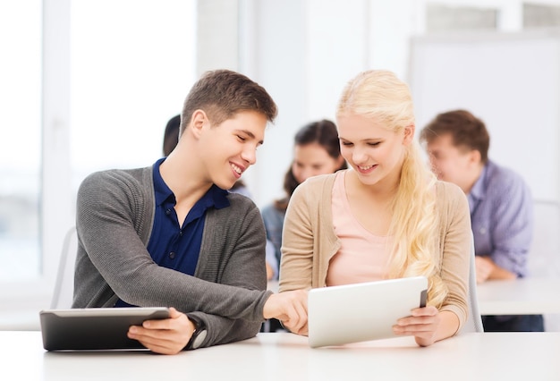 Educación, tecnología e Internet: dos estudiantes sonrientes mirando tablet pc en una conferencia en la escuela