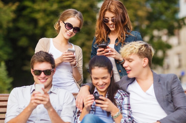 educación, tecnología, internet, vacaciones de verano, redes sociales y concepto adolescente - grupo de adolescentes con teléfonos inteligentes