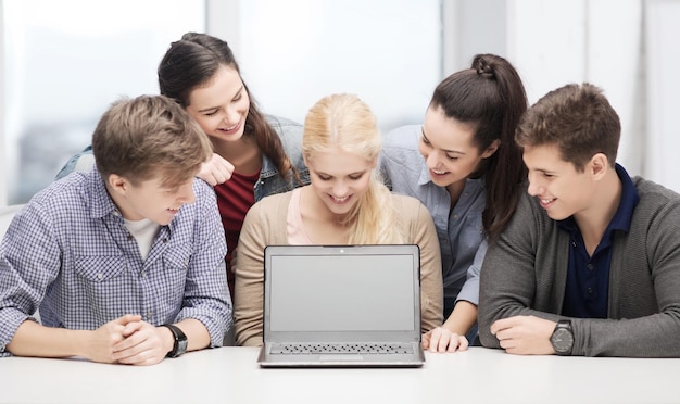 educación, tecnología, publicidad y concepto de Internet - grupo de estudiantes sonrientes mirando la pantalla de un portátil negro en blanco