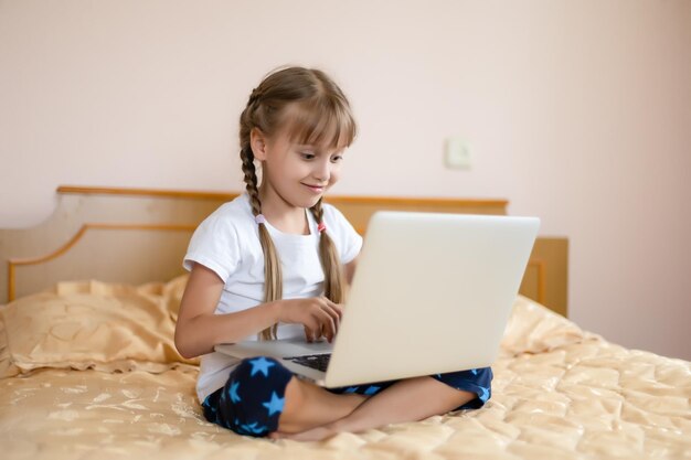 Educación, tiempo libre, tecnología e internet concepto - niña estudiante con ordenador portátil en casa