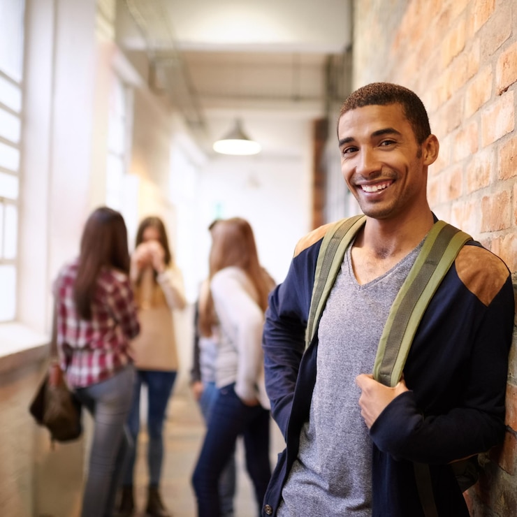 Foto educación universitaria y retrato del hombre en el campus listo para estudiar conocimiento y aprender beca feliz y rostro de estudiante masculino en el pasillo con amigos para la academia escolar y la clase universitaria
