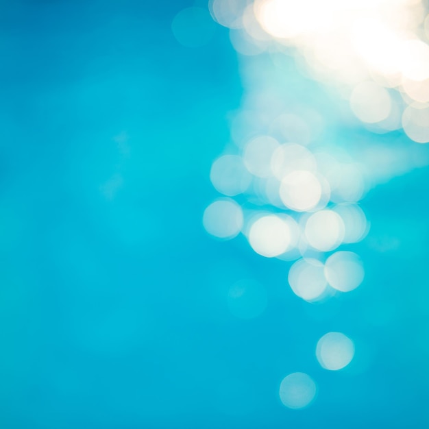 Efectos de luz bokeh de enfoque suave sobre un fondo de agua azul ondulado en la piscina