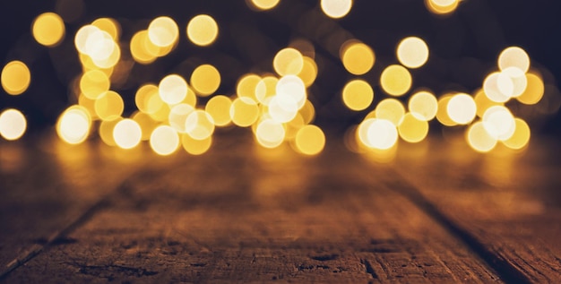 Efeito de luzes de bokeh de natal na mesa de madeira, incluindo espaço de cópia. ideal para layouts de sites e revistas