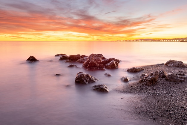 Efeito de seda na água de uma praia ao pôr do sol