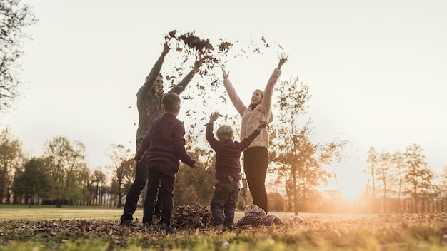 Efeito retrô imagem desbotada e tonificada de uma família brincando com folhas de outono na natureza