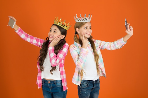 Egozentrische Prinzessin. Kinder tragen goldene Kronen-Symbolprinzessin. Warnzeichen für verwöhntes Kind. Vermeide es, verwöhnte Kinder großzuziehen. Mädchen, die Selfie-Foto-Smartphone-Kamera machen. Konzept für verwöhnte Kinder.