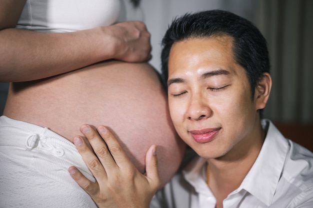 Ehemann, der auf den Bauch seiner Frau hört