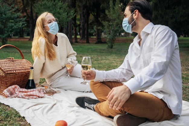 Ehemann und Ehefrau mit medizinischen Masken beim gemeinsamen Picknick