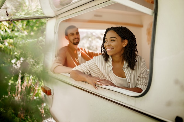 Ehemann und Ehefrau schauen aus dem Wohnmobilfenster und campen in einem Wohnwagen. Mann und Frau reisen mit dem Van, romantische Ferien mit dem Wohnmobil, Wohnmobile in Wohnmobilen