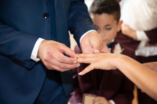 Ehering in der Hand der Braut, Frau, auf die Finger des Bräutigams, die Hände des Mannes, traditioneller Hochzeitstag