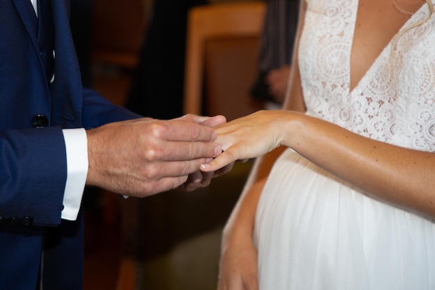 Ehering in der Hand des Bräutigams, die am Tag der Hochzeit auf den Finger der Braut gelegt wird