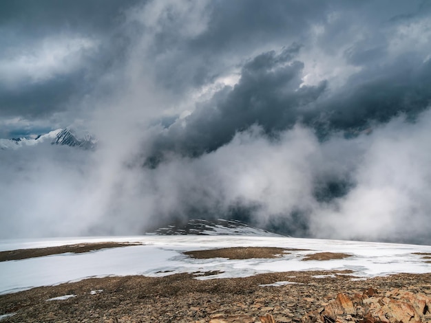 Ehrfürchtiger Sturm, eine schneebedeckte atmosphärische Front in den Bergen. Atmosphärischer Alpenblick auf die Schneebergkette mit niedrigen Wolken. Szenische Landschaft mit schönen Schneebergen in niedrigen Wolken.