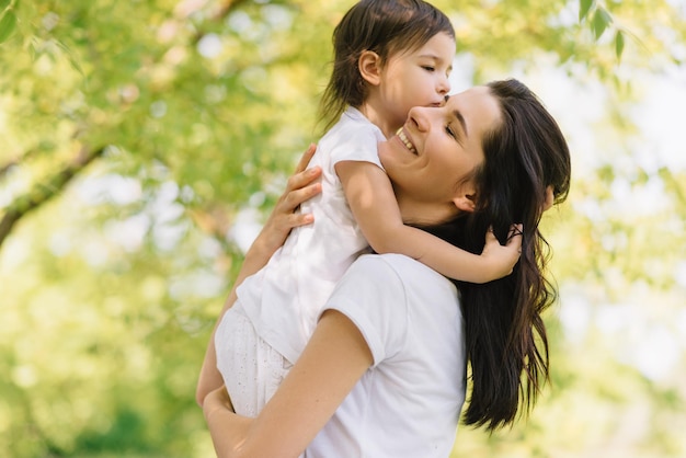 Ehrliche Aufnahme einer fröhlichen, schönen Mutter und ihrer süßen Tochter, die im Freien spielen und sich gegenseitig halten Mutter und ihr hübsches Kind, das zusammen im Park spielt Porträt einer guten Beziehung in der Familie