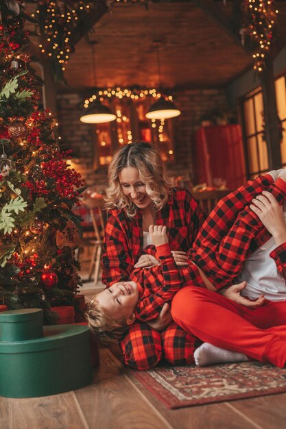 Ehrliche, authentische, süße, glückliche Familie in rot karierten Pyjamas verbringt Zeit zusammen in der weihnachtlich dekorierten Lodge