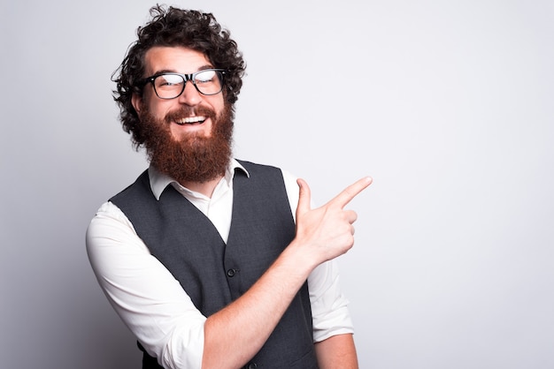 Ei, mano, olhe para esta oferta, homem barbudo hipster de terno apontando para copyspace