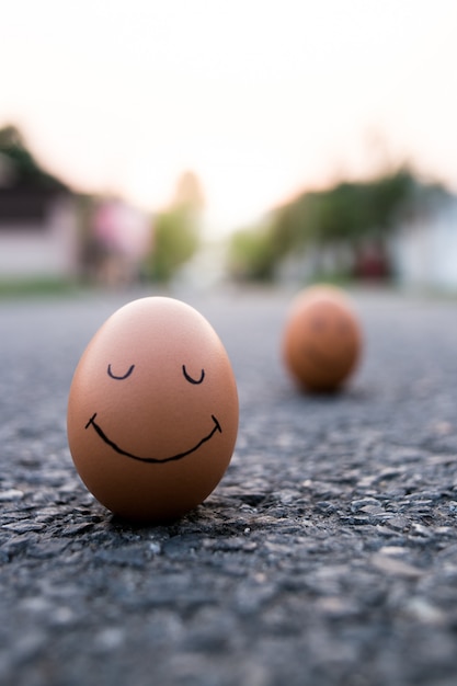 Ei mit gezogenem traurigem Gesicht nahe den glücklichen auf Fahrbahn. Depressionsgefahr