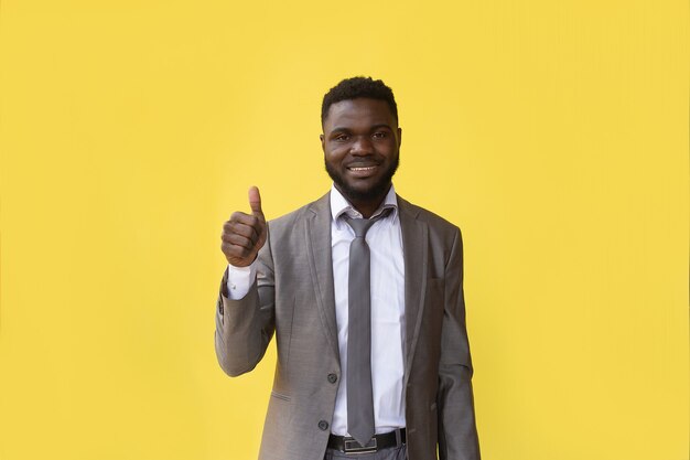 Ei você. cara africana positiva, apontando os dedos para a câmera posando sobre fundo amarelo. foto de estúdio