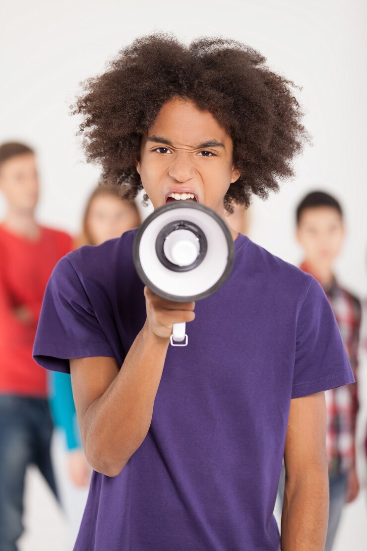 Ei você! Jovem adolescente africano gritando com o megafone enquanto seus amigos estão parados no fundo